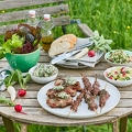116721 Gedeckter Gartentisch mit gegrilltem Fleisch und Salaten