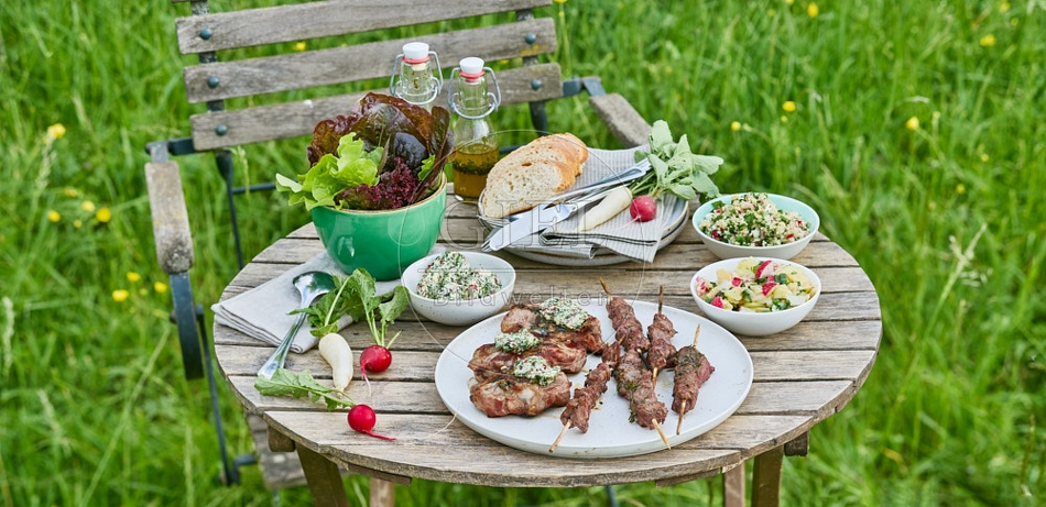 116722 Gedeckter Gartentisch mit gegrilltem Fleisch und Salaten