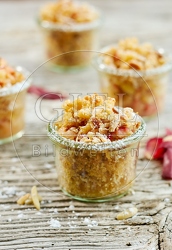 118139 Vier hausgemachte Apfelcrumbles in Gläsern auf rustikalem Holztisch