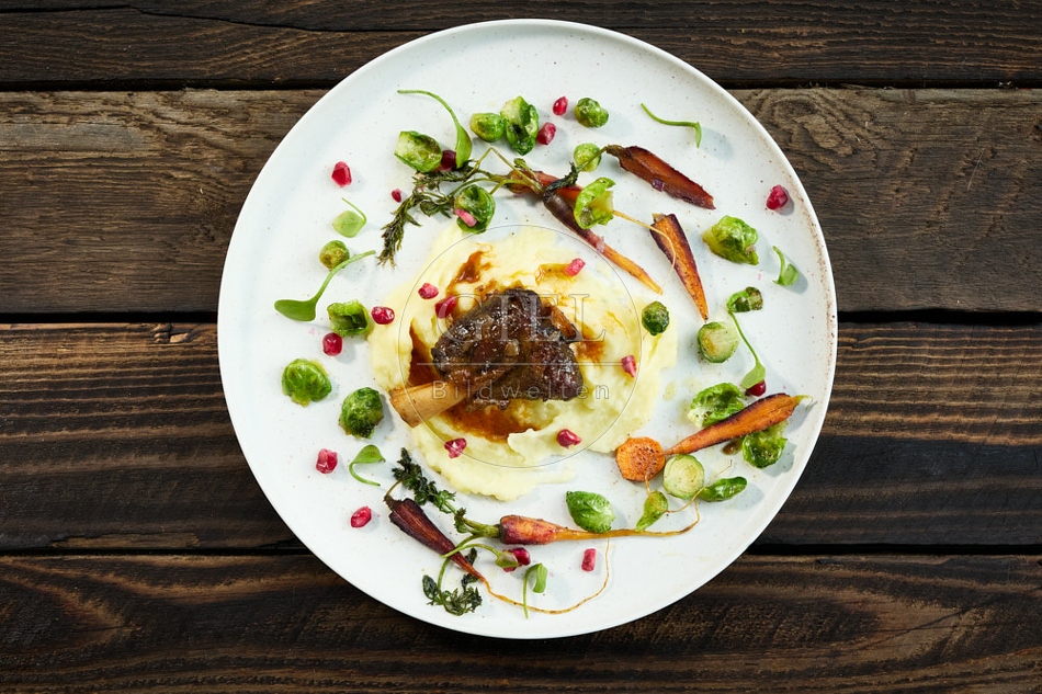 118140 Ziegenhäxle mit Sellerie-Kartoffelpüree und gebratenes Wintergemüse auf rustikalem Holz